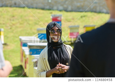 A diverse group of young friends and entrepreneurs explore small honey production businesses in the natural setting of the countryside. 114880458