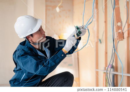Electrician doing wiring work at a construction site Electrician doing wiring work at a construction site 114880541