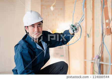 Electrician doing wiring work at a construction site Electrician doing wiring work at a construction site 114880544