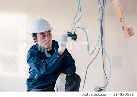 Electrician doing wiring work at a construction site 114880551