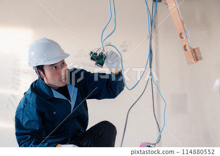 Electrician doing wiring work at a construction site 114880552