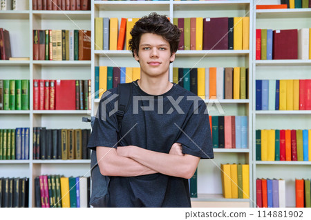 Portrait of college student guy with crossed arms inside library of educational building Portrait of college student guy with crossed arms inside library of educational building 114881902