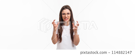 Waist-up of hateful and pissed-off, annoyed young female telling about person she hates, clench hands into fists, cursing, swearing at guy, want strangle someone from annoyance, white background Waist-up of hateful and pissed-off, annoyed young female telling about person she hates, clench hands into fists, cursing, swearing at guy, want strangle someone from annoyance, white background 114882147