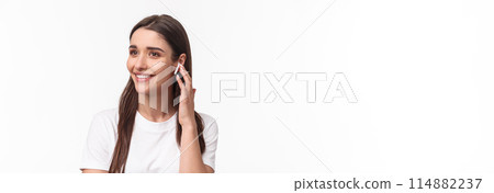 Close-up portrait of attractive smiling young brunette woman talking on phone, using wireless earphone to contact friend, looking away carefree, listening music in headphones, white background Close-up portrait of attractive smiling young brunette woman talking on phone, using wireless earphone to contact friend, looking away carefree, listening music in headphones, white background 114882237