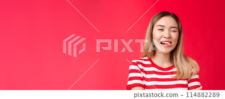 Close-up sassy carefree outgoing urban asian female student enjoy summer vacation wear striped t-shirt, show tongue playfully winking camera, stand red background positive friendly mood Close-up sassy carefree outgoing urban asian female student enjoy summer vacation wear striped t-shirt, show tongue playfully winking camera, stand red background positive friendly mood 114882289