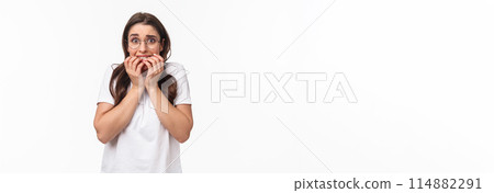 Waist-up portrait of scared young brunette girl in panic, exams are near feel frightened, biting fingers and staring terrified, trembling fear, standing white background afraid Waist-up portrait of scared young brunette girl in panic, exams are near feel frightened, biting fingers and staring terrified, trembling fear, standing white background afraid 114882291