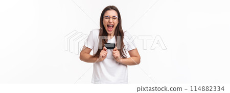 Portrait of excited female shopaholic cant wait to waste all money on her bank account, got new credit card, screaming from excitement and thrill, happy to shopping her favorite online store Portrait of excited female shopaholic cant wait to waste all money on her bank account, got new credit card, screaming from excitement and thrill, happy to shopping her favorite online store 114882334