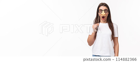 Entertainment, fun and holidays concept. Funny and cute young girl fool around, praying wearing glasses and nose mask, gasping amazed, look surprised standing white background Entertainment, fun and holidays concept. Funny and cute young girl fool around, praying wearing glasses and nose mask, gasping amazed, look surprised standing white background 114882366
