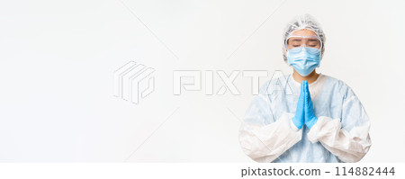 Hopeful asian female doctor or nurse in personal protective equipment and face mask, hoping, praying for smth, standing over white background Hopeful asian female doctor or nurse in personal protective equipment and face mask, hoping, praying for smth, standing over white background 114882444