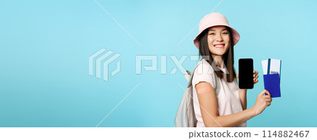 Happy smiling tourist got vaccine from covid-19, showing mobile phone screen and passport with tickets to travel abroad, vaccination certificate on smartphone app Happy smiling tourist got vaccine from covid-19, showing mobile phone screen and passport with tickets to travel abroad, vaccination certificate on smartphone app 114882467