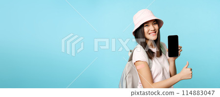 Smiling asian tourist shows arm with patch from covid-19 vaccination, showing coronavirus vaccine international certificate on smartphone app, thumbs up 114883047