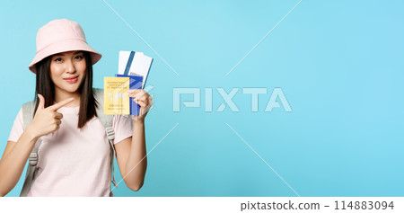Smiling korean tourist shows her passport, vaccination certificate from coronavirus disease, getting vaccine shot to travel, standing over blue background Smiling korean tourist shows her passport, vaccination certificate from coronavirus disease, getting vaccine shot to travel, standing over blue background 114883094
