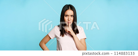 Angry asian woman shushing, frowning in disapproval and hushing, taboo sign, silence gesture, standing over blue background Angry asian woman shushing, frowning in disapproval and hushing, taboo sign, silence gesture, standing over blue background 114883133