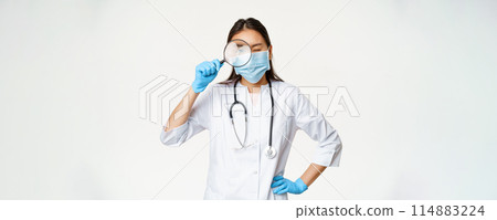 Asian female doctor looking through magnifying glass, examine patient, searching disease, wearing medical mask and rubber gloves, white background Asian female doctor looking through magnifying glass, examine patient, searching disease, wearing medical mask and rubber gloves, white background 114883224