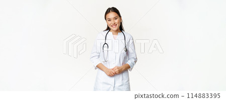 Smiling asian woman doctor, wearing medical robe and stethoscope, looking pleasant at patient, standing over white background Smiling asian woman doctor, wearing medical robe and stethoscope, looking pleasant at patient, standing over white background 114883395