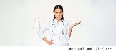 Confused asian woman doctor cant understand patient, looking puzzled and annoyed, raising hand up questioned pose, standing in medical uniform over white background Confused asian woman doctor cant understand patient, looking puzzled and annoyed, raising hand up questioned pose, standing in medical uniform over white background 114883560