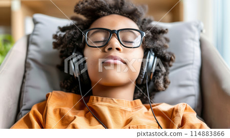 Young Boy Relaxing with Headphones at Home, Enjoying Music or Podcast, Capturing Relaxation and Leisure 114883866