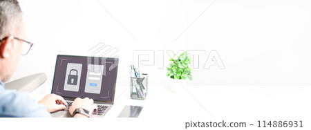 A man is typing on a laptop with a password screen open 114886931