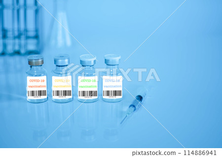 Four bottles of vaccine with a syringe next to them 114886941