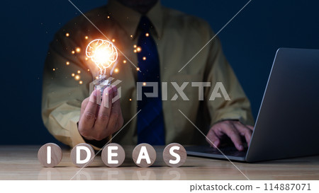 A man is holding a light bulb and the words "ideas" are written in front of him A man is holding a light bulb and the words "ideas" are written in front of him 114887071