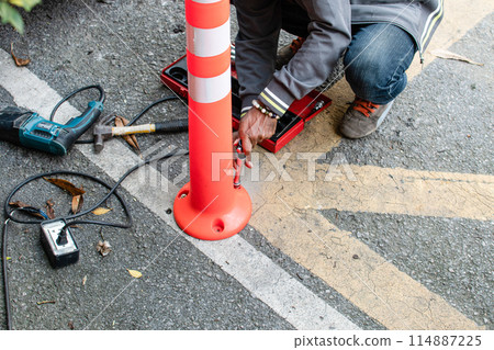 A man is fixing a red and white traffic sign A man is fixing a red and white traffic sign 114887225