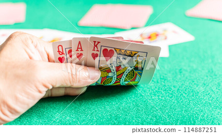 A hand holding a deck of cards with the King of Hearts and Queen of Hearts 114887251