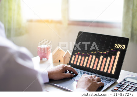 A man is typing on a laptop with a graph of the stock market on the screen A man is typing on a laptop with a graph of the stock market on the screen 114887272