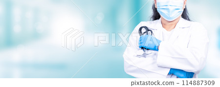 A woman in a white lab coat is wearing a blue glove and a mask 114887309