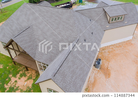 Rubber asphalt roof shingles are being used to cover construction roof of new house Rubber asphalt roof shingles are being used to cover construction roof of new house 114887344
