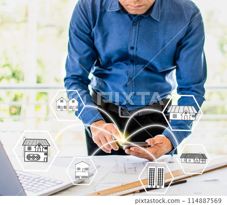 A man is looking at a phone with a house icon on it 114887569