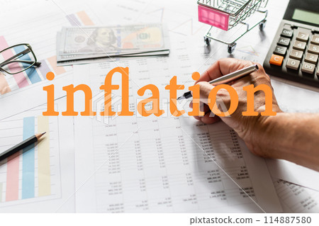 A person is writing the word inflation on a piece of paper A person is writing the word inflation on a piece of paper 114887580