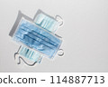 A blue and white face mask is laying on a white surface 114887713