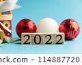 A blue background with a red and white Christmas ornament and a red 114887720