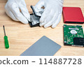 A person is working on a computer hard drive 114887728