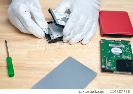 A person is working on a computer hard drive 114887728