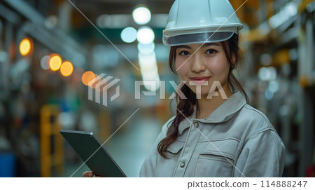 A woman operating a tablet in a factory 114888247