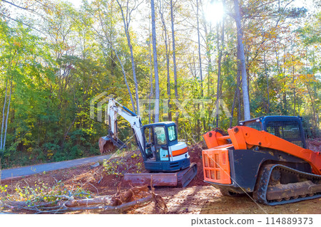 An uprooted tree is uprooted by tractor during construction, preparing land for building An uprooted tree is uprooted by tractor during construction, preparing land for building 114889373
