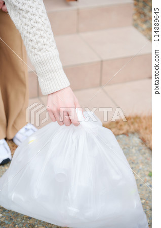 A woman taking out the trash at the entrance 114889645