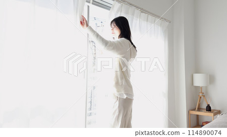 A woman opening the curtains in the morning 114890074
