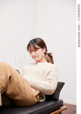 A woman operating a smartphone at home A woman operating a smartphone at home 114890491