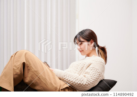 A woman operating a smartphone at home A woman operating a smartphone at home 114890492