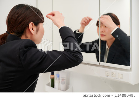 Business woman getting ready in front of the mirror 114890493