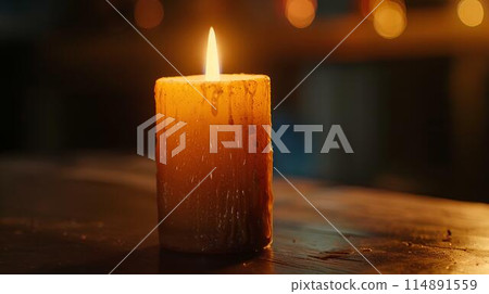 Candle burning on table in dark room. The evening lighting illuminates the candle flame. A heartwarming, peaceful and romantic concept background with copy space area. Bright orange light from the lit Candle burning on table in dark room. The evening lighting illuminates the candle flame. A heartwarming, peaceful and romantic concept background with copy space area. Bright orange light from the lit 114891559