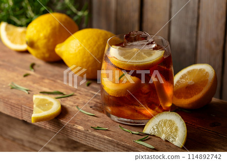 Iced tea or alcoholic cocktail with ice, rosemary and lemon slices on a old wooden table. 114892742