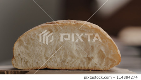 slicing ciabatta on olive wood board closeup slicing ciabatta on olive wood board closeup 114894274