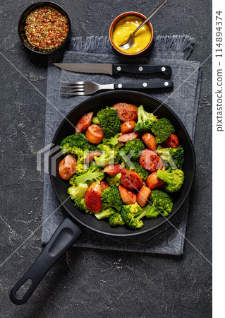 fried juicy sausage and crispy broccoli in skillet 114894374