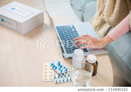 Sick young woman sit on sofa video call online with laptop consult with doctor at home, female covered blanket searching instructions for medical use medications in internet, healthcare and technology 114896101