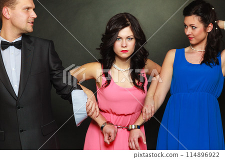 Wife and husband in handcuffs woman standing behind Wife and husband in handcuffs woman standing behind 114896922