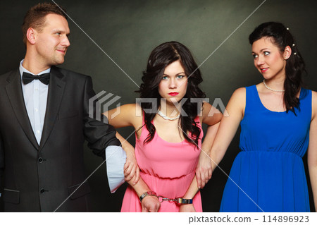 Wife and husband in handcuffs woman standing behind 114896923