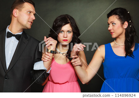 Wife and husband in handcuffs woman standing behind Wife and husband in handcuffs woman standing behind 114896924